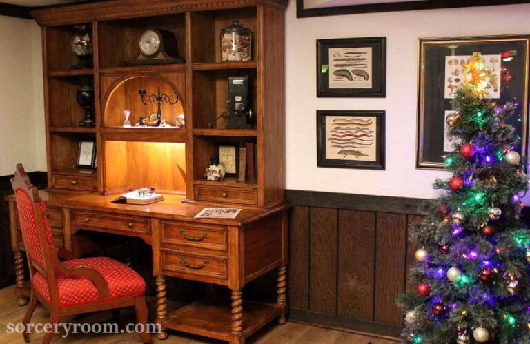 Harry Potter themed room with a large oak desk and hutch, Gryffindor red upholstered chair, Hogwarts themed accessories on the shelves, framed natural prints on the walls, and a Christmas tree in the corner