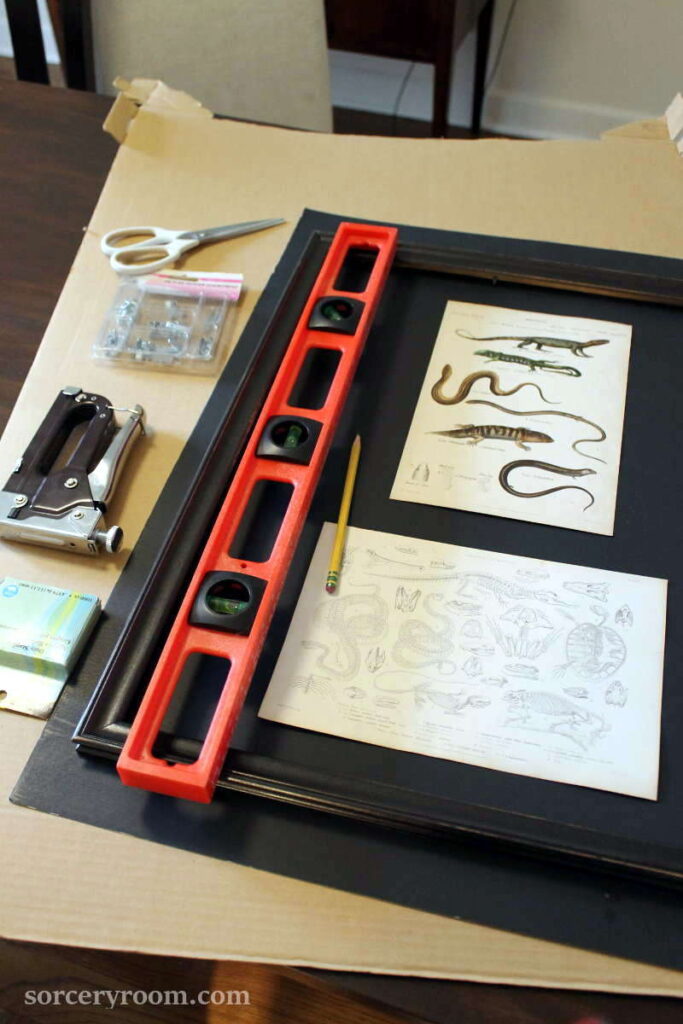 Tools: prints, black paper, frame, ruler, pencil, scissors, stapler, cardboard.