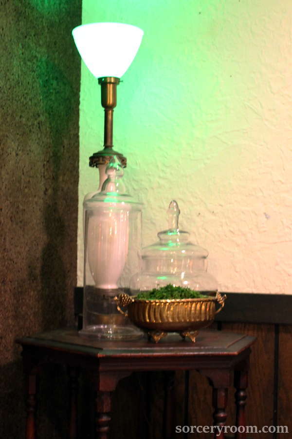 glass jars, brass vase with moss, white lamp on a side table