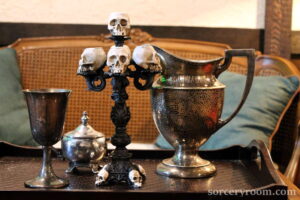 silver goblet, silver sugar bowl, skull candelabra, sliver pitcher on a tray