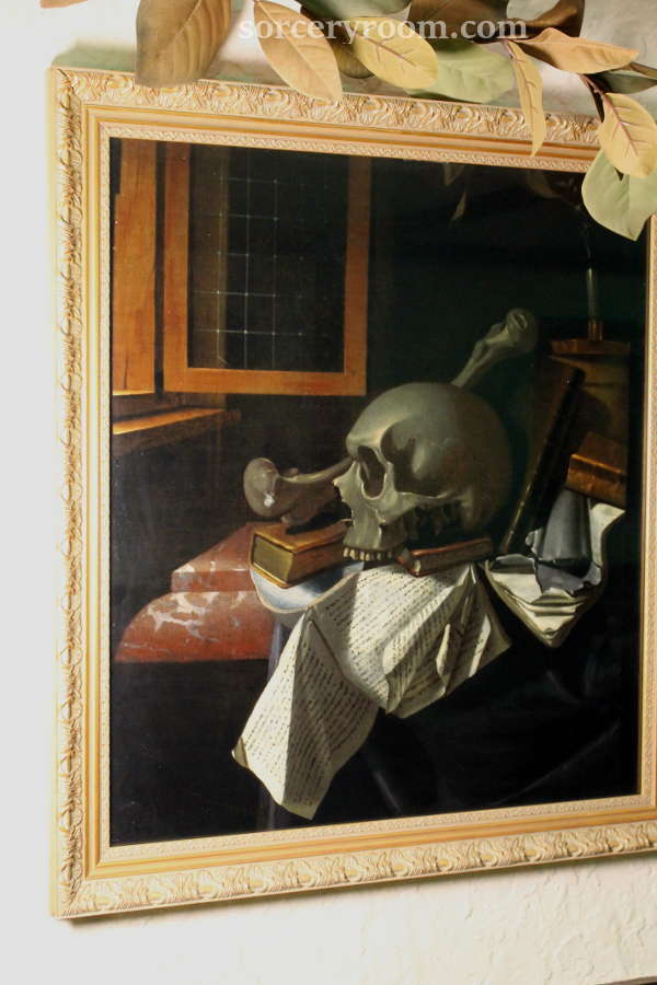 Painting with a skull and books in a gold frame