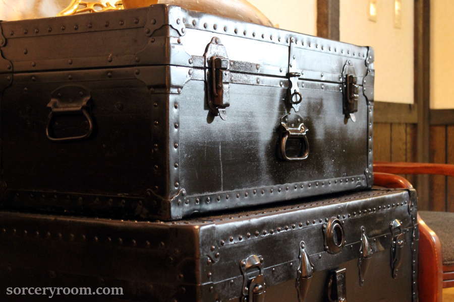 Two stacked black steamer trunks