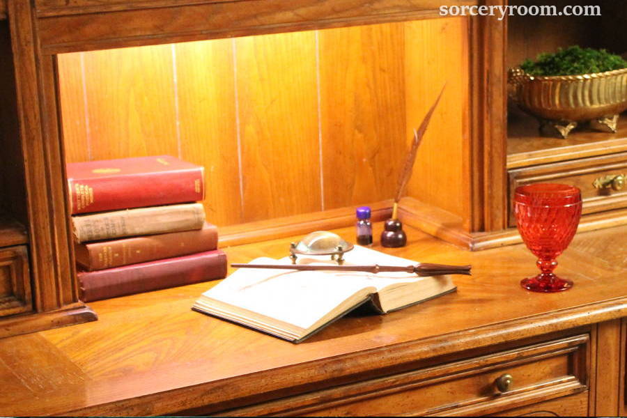 Books on a desk, magic wand, magnifying glass, ink and quill