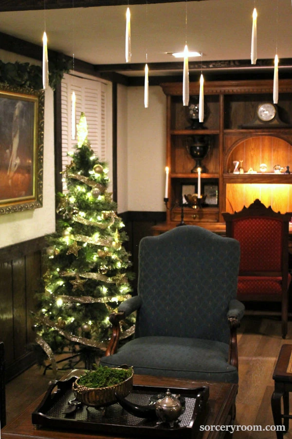 Harry Potter Christmas tree - dim and moody sorcery themed room with a Hogwarts style tree in the background and floating candles above the seating area