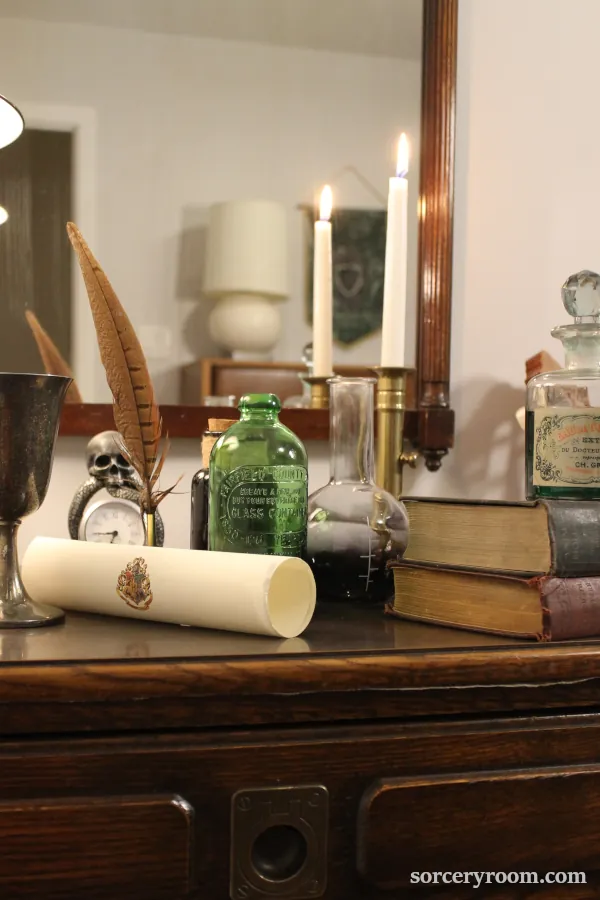 Harry Potter décor - potion bottles on a dresser, with old books, a brass candle holder, Hogwarts scroll, quill on a dresser