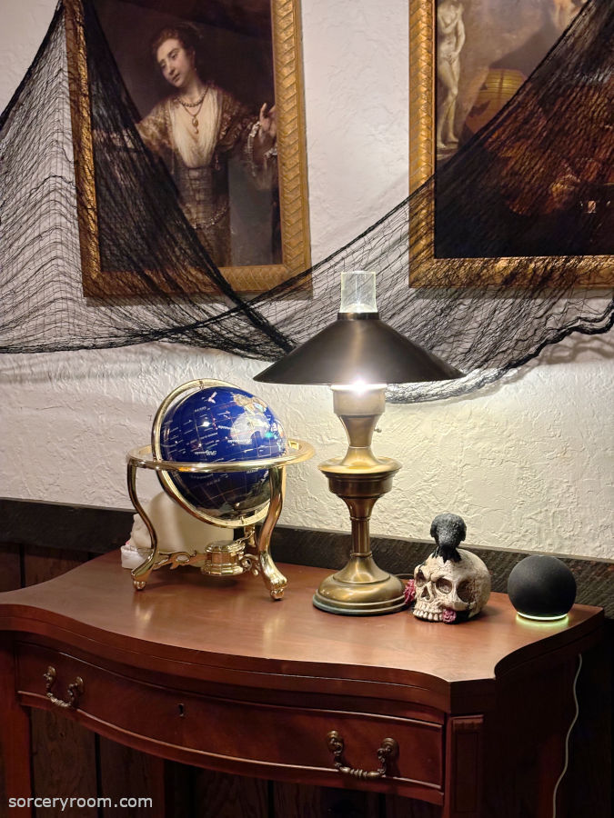 Harry Potter themed Halloween décor - entry table with skull décor, a globe, and old lamp, decorated with Halloween netting