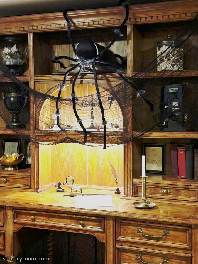 Harry Potter themed Halloween décor - a large decorative spider appears to be crawling down a sorcery inspired desk and hutch